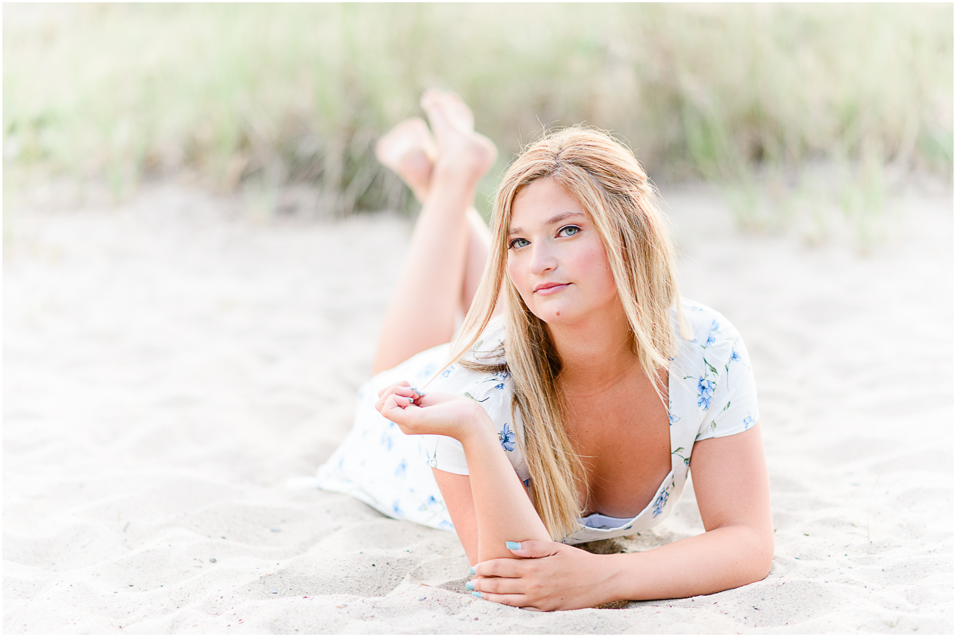 Photo by Marshfield senior portrait photographer Christina Runnals | High school girl wearing a white dress and laying in the sand on the beach