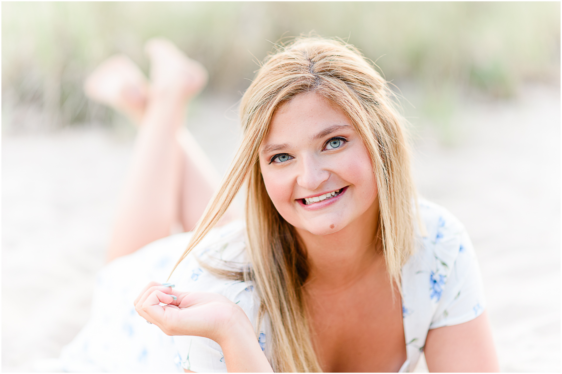 Photo by Marshfield senior portrait photographer Christina Runnals | High school girl wearing a white dress and laying in the sand on the beach