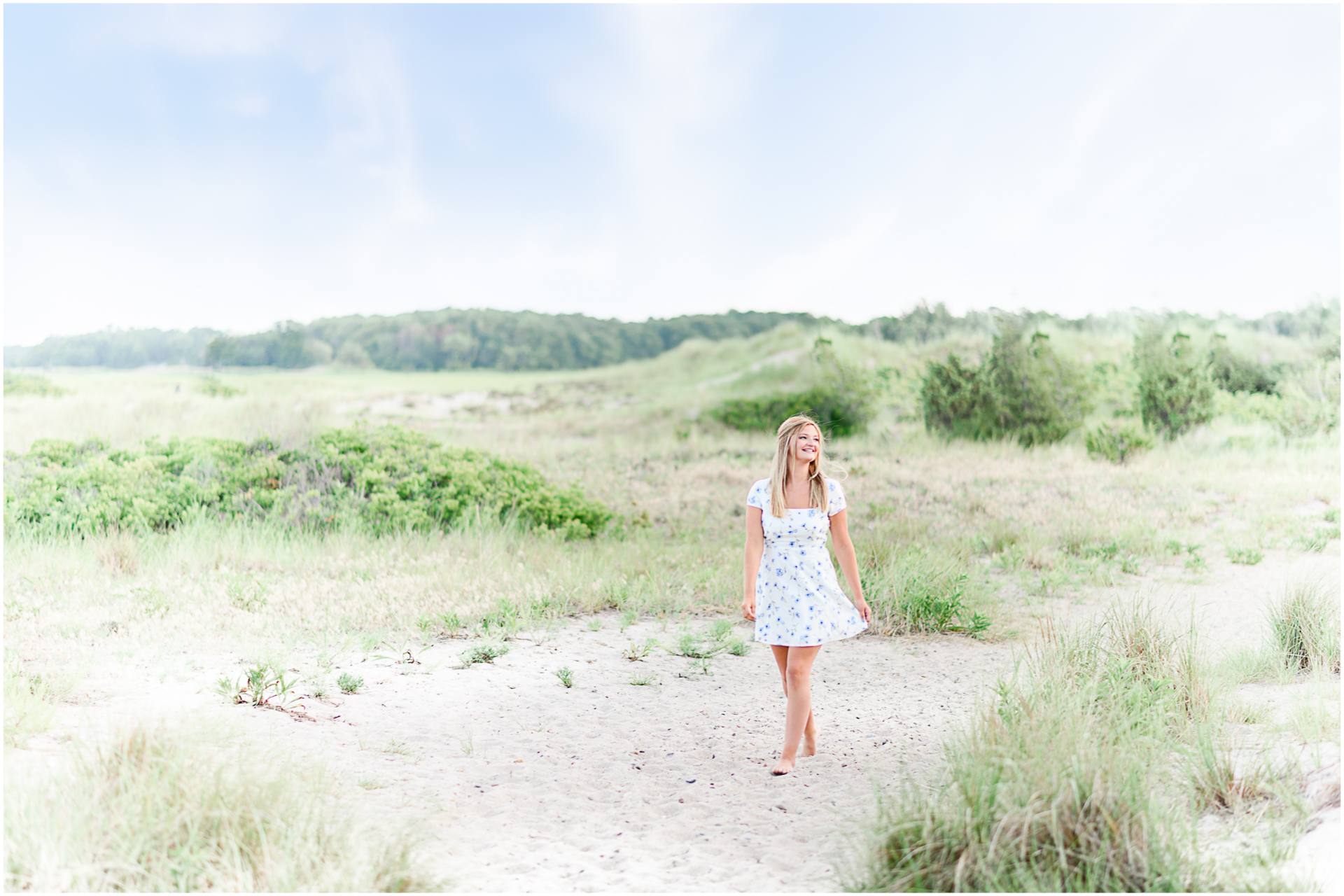 Photo by Marshfield senior portrait photographer Christina Runnals | High school girl wearing a white dress and walking along the sand at the beach