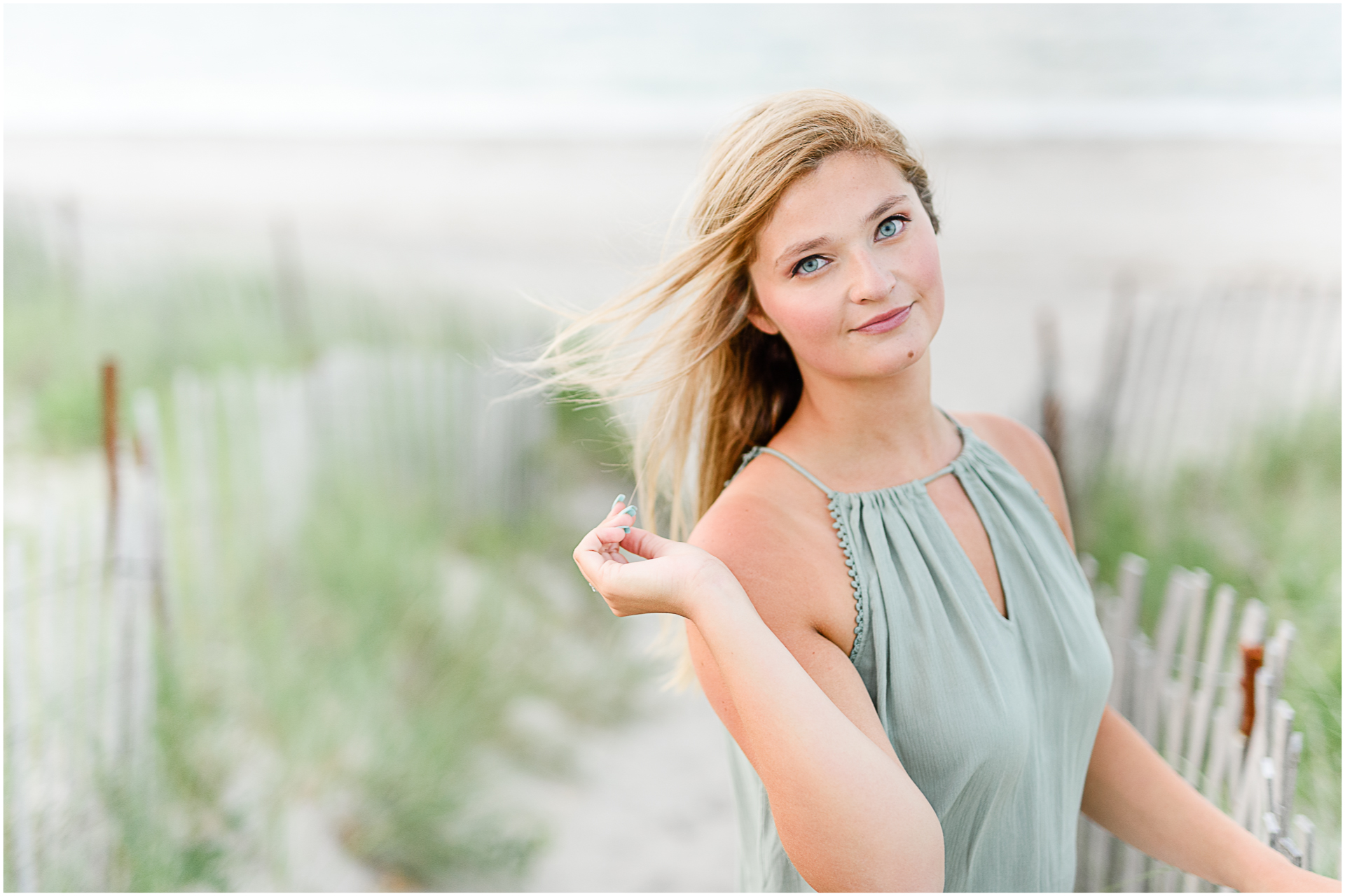 Photo by Marshfield senior portrait photographer Christina Runnals | High school girl standing in front of a fence at the beach