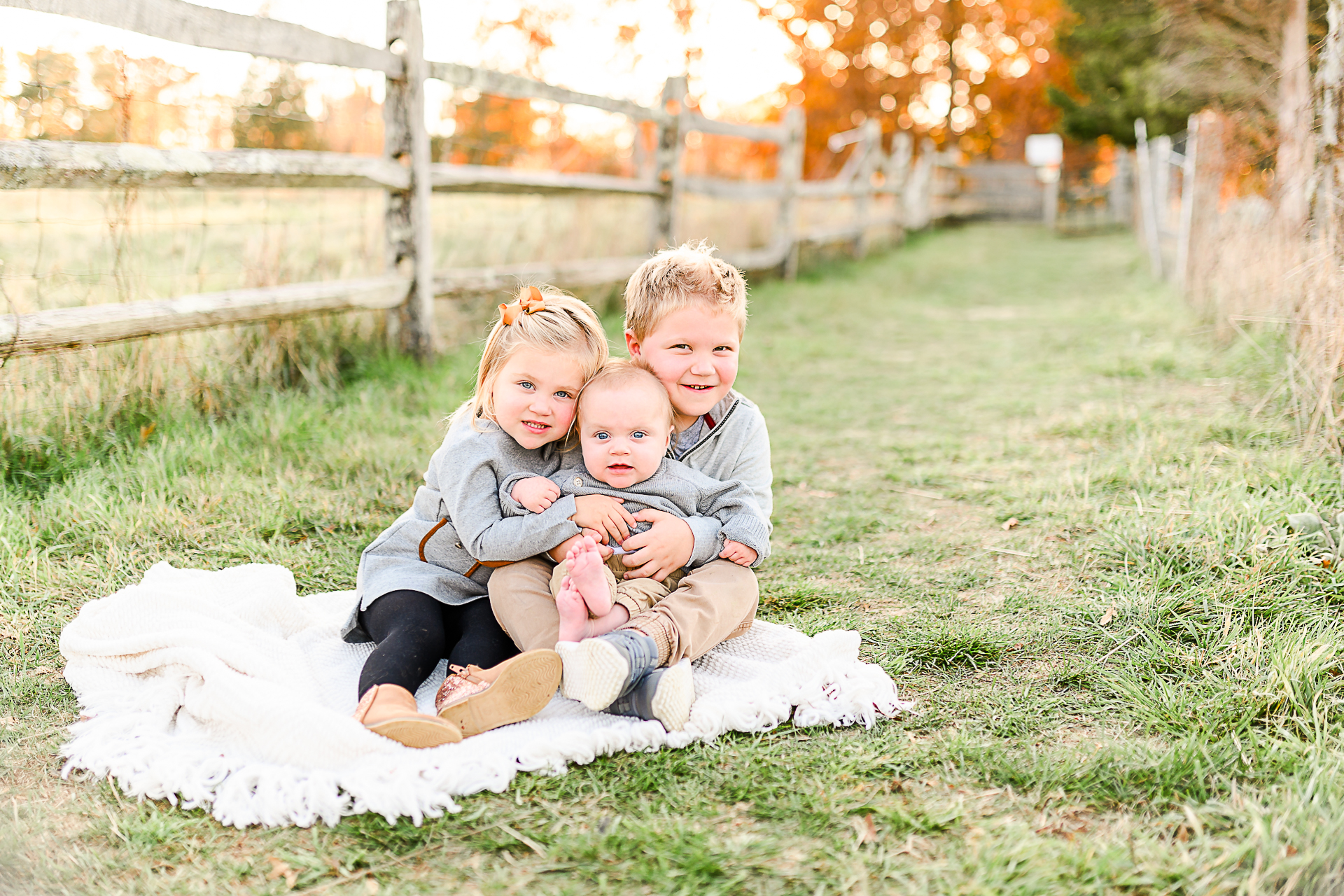 Photo by Norwell Photographer Christina Runnals | A boy, girl, and baby sitting on a white blanket smiling for a picture