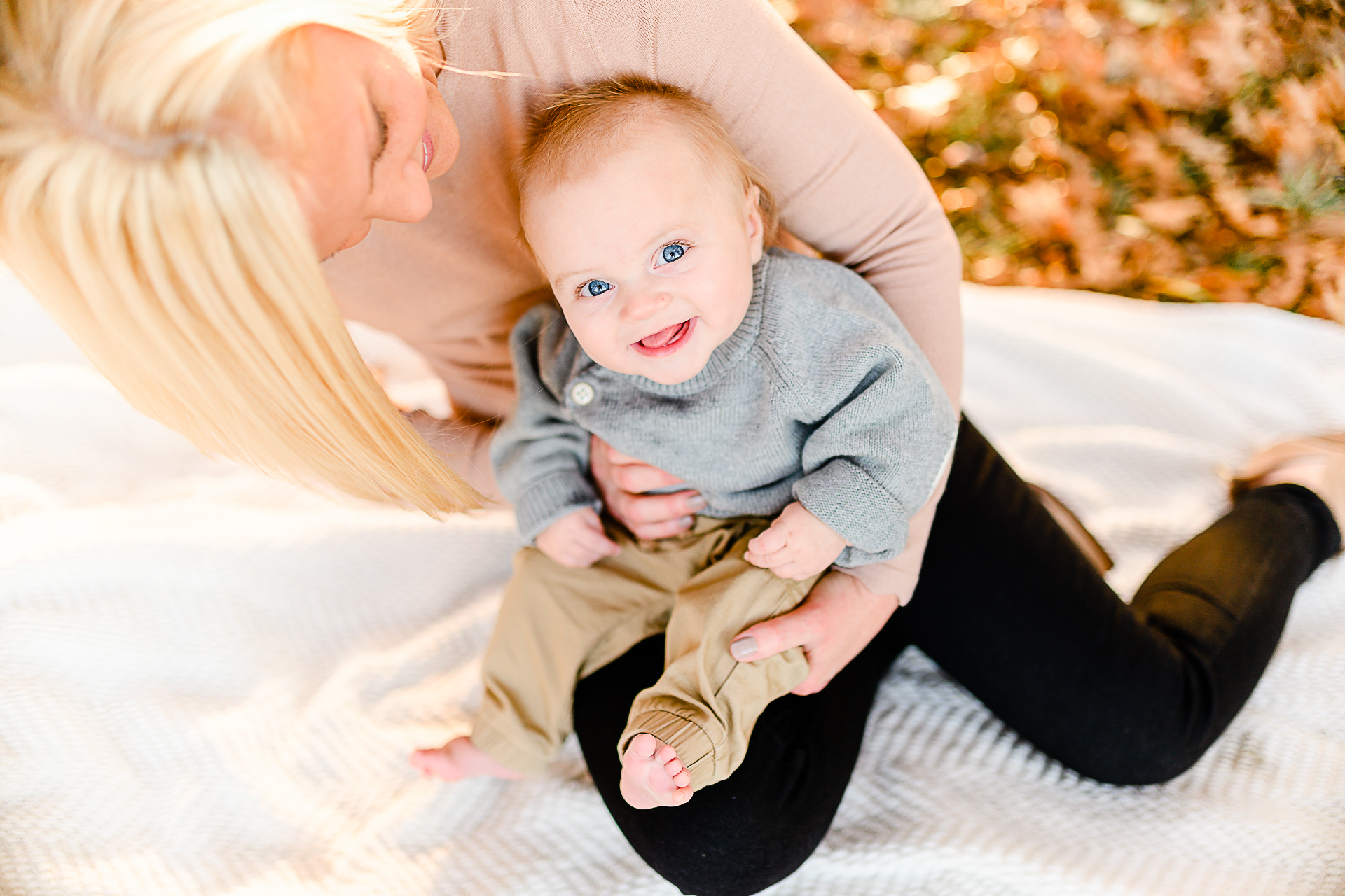 Photo by Norwell Photographer Christina Runnals | Mom holding her baby who is looking up at the camera with big blue eyes and smiling.