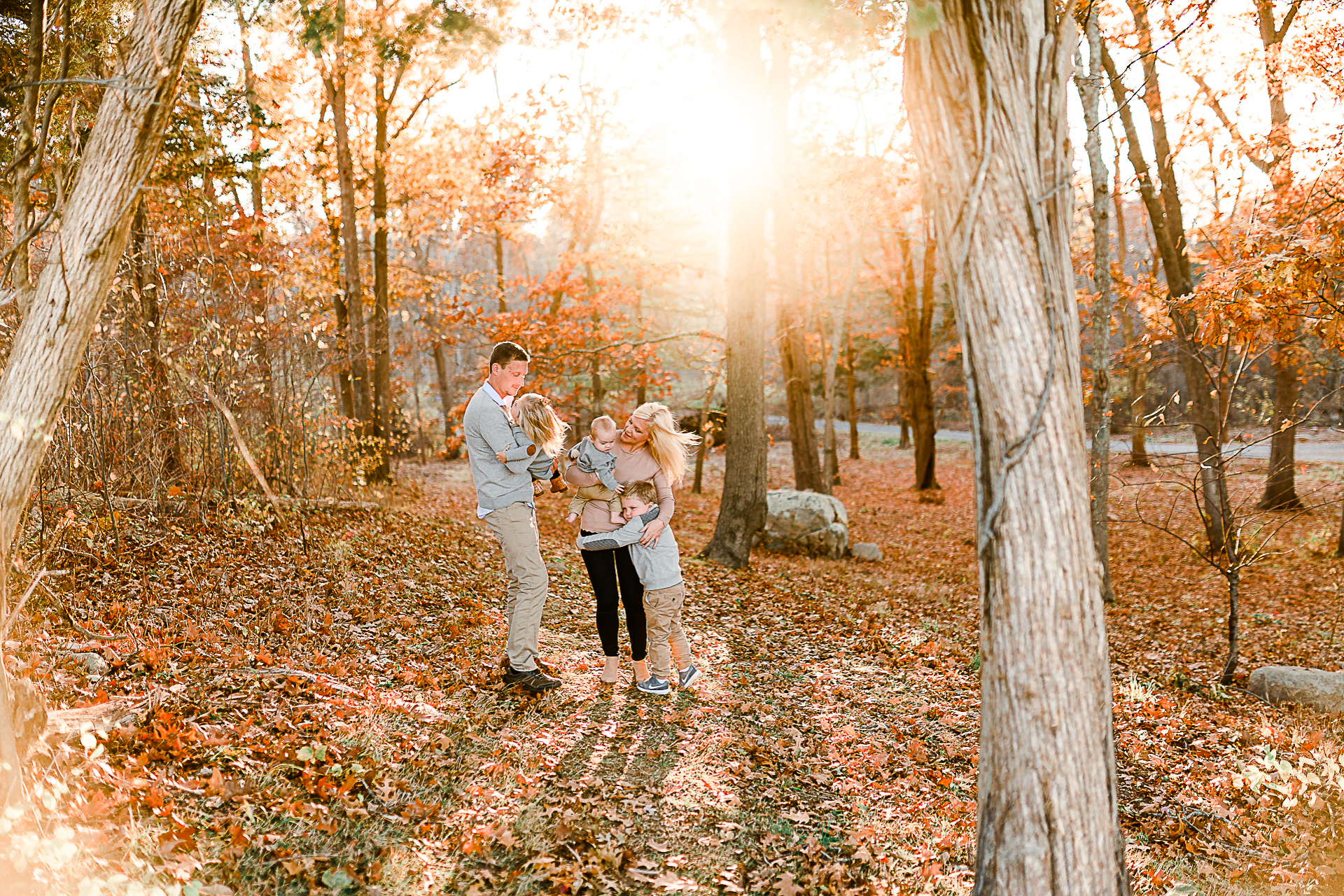 Photo by Norwell Photographer Christina Runnals | Family dancing in an autumn forest with sunlight streaming through the trees