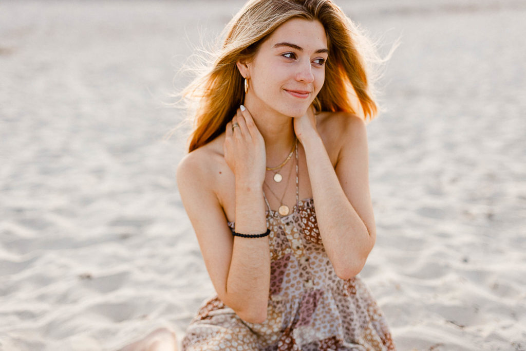 Photo by Cohasset senior portrait photographer Christina Runnals | High school senior girl sitting on the beach at sunset