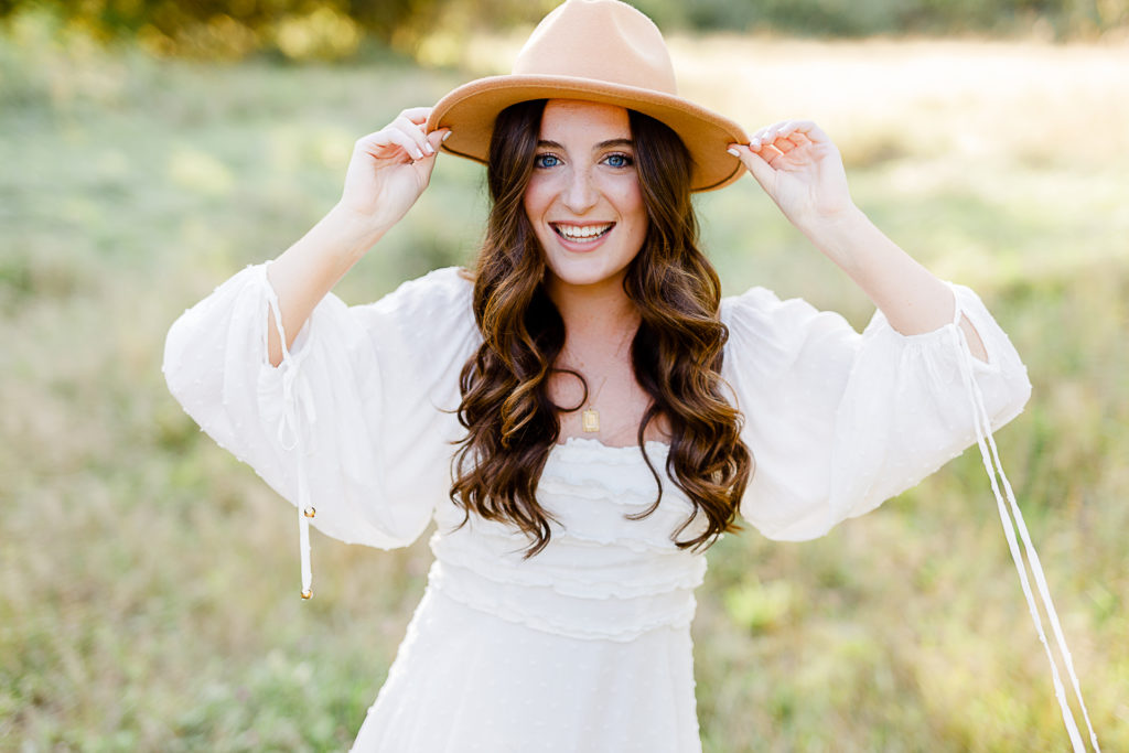 Photo taken by Massachusetts senior photographer Christina Runnals | High school senior girl standing in field wearing hat