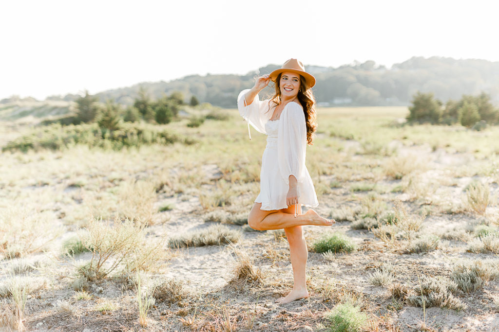 Lily Class of 2022 taken by Christina Runnals Senior Photographer | High school senior girl wearing a hat dancing in a field