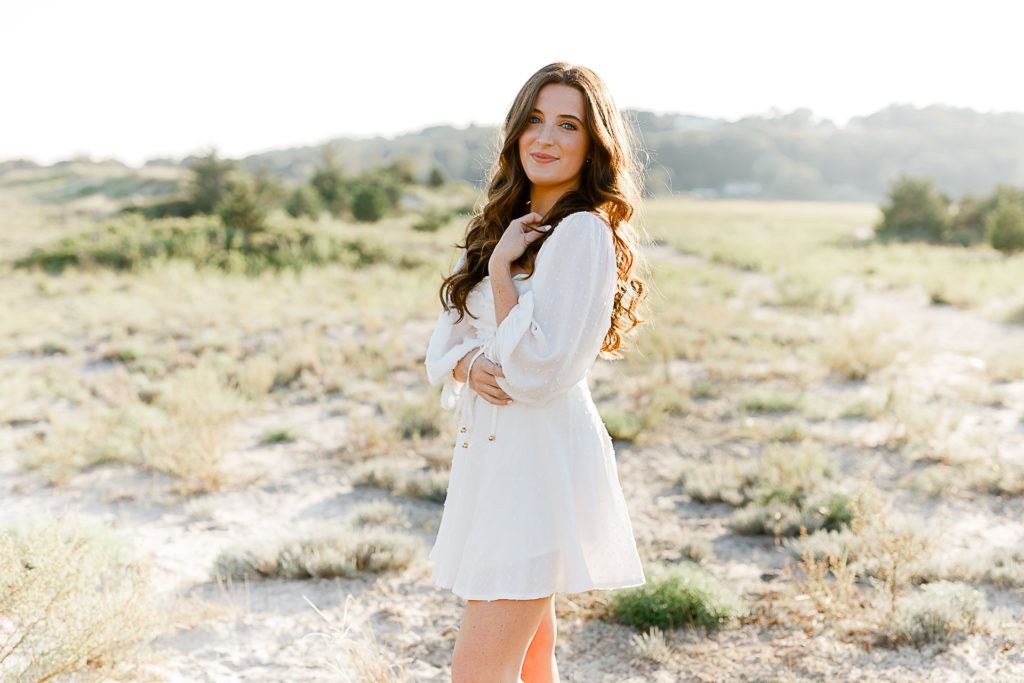 Beach picture by senior photographer Christina Runnals | | High school senior girl standing in a field wearing a white dress