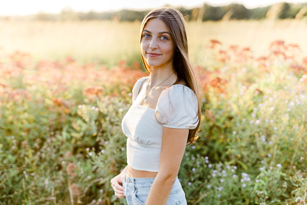 Photo by Scituate Senior Photographer Christina Runnals | High school senior girl standing n a wildflower field laughing