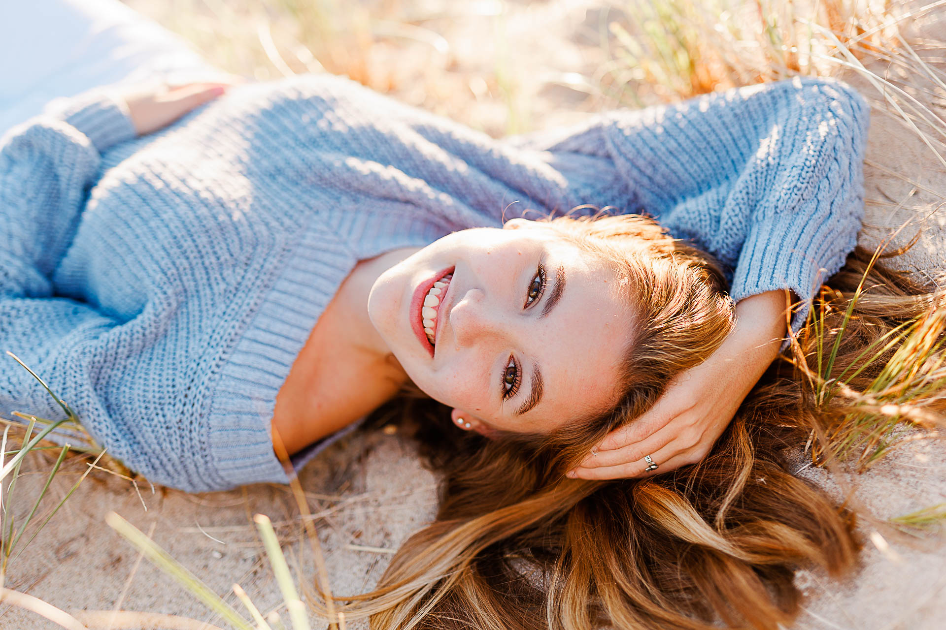 Photo by Cohasset senior photographer Christina Runnals | High school senior girl laying on the sand at a Cohasset beach and smiling