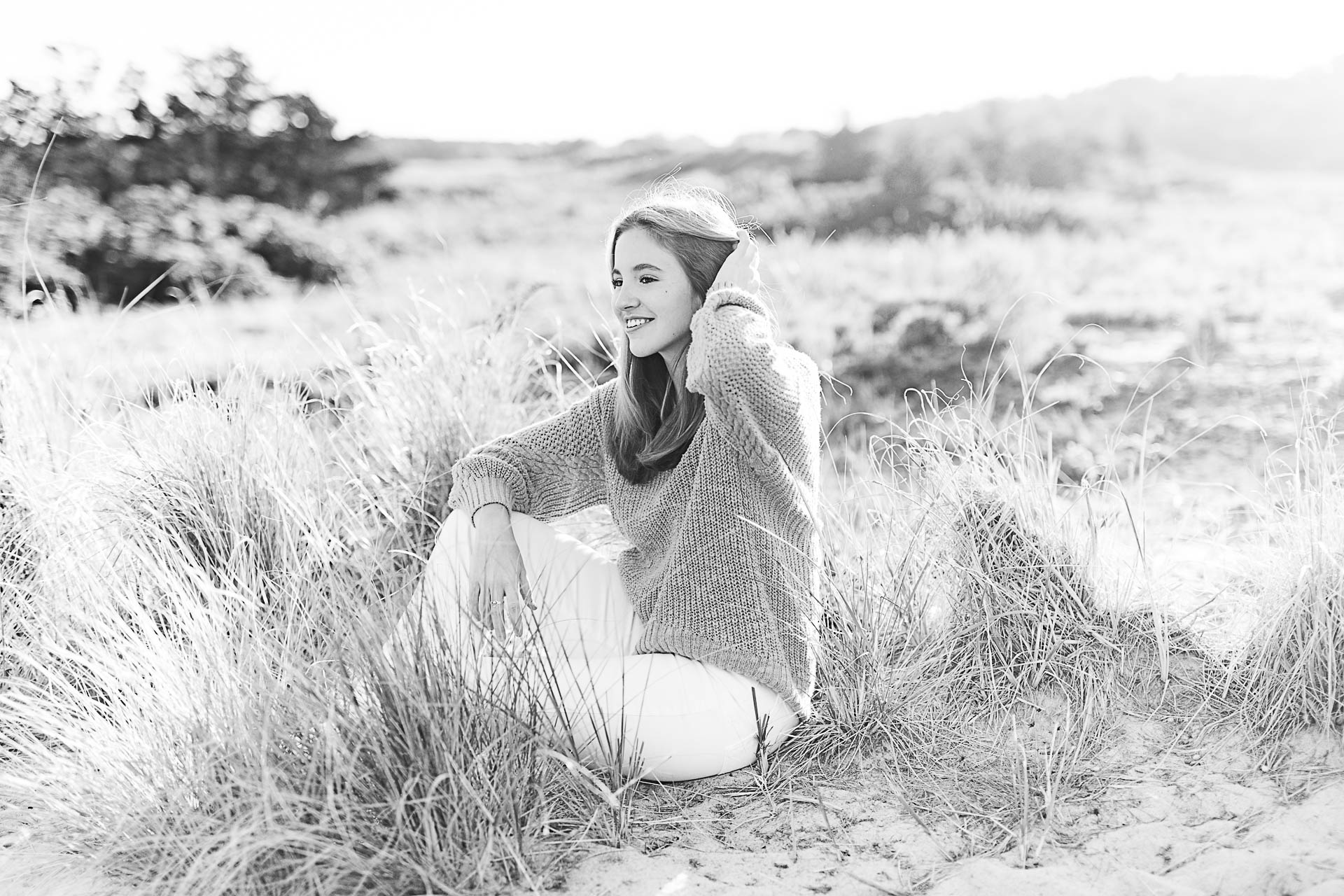 Photo by Cohasset senior photographer Christina Runnals | High school senior girl sitting in beach grass and looking into the distance