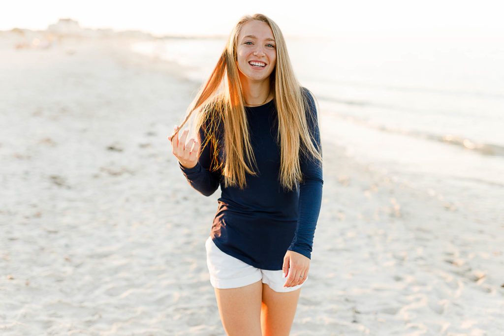 Photo by Plymouth Massachusetts Photographer Christina Runnals | High school senior girl walking along the beach and playing with her hair