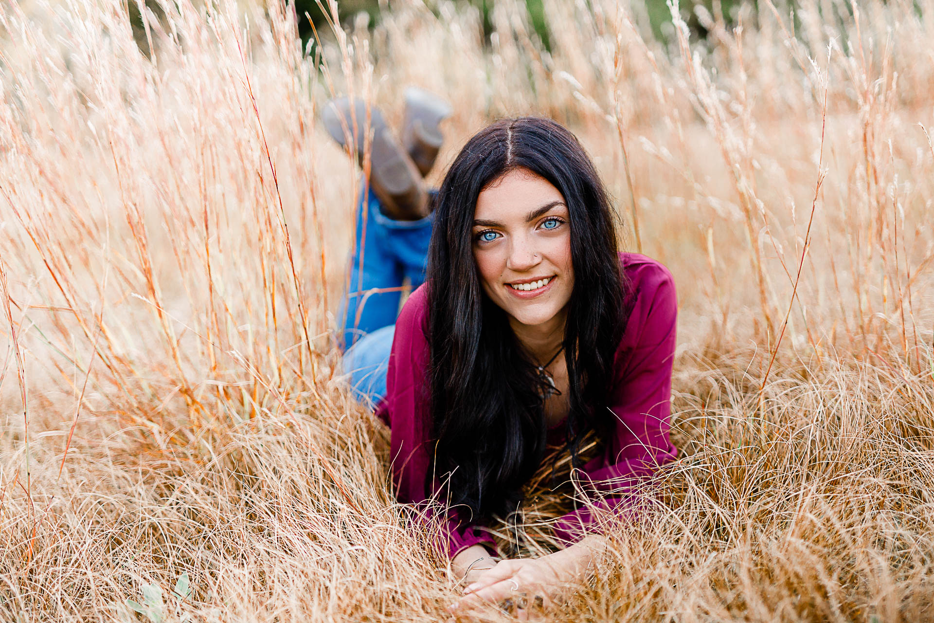Photo by Duxbury senior photographer Christina Runnals | A high school senior girl with big blue eyes laying in a field smiling