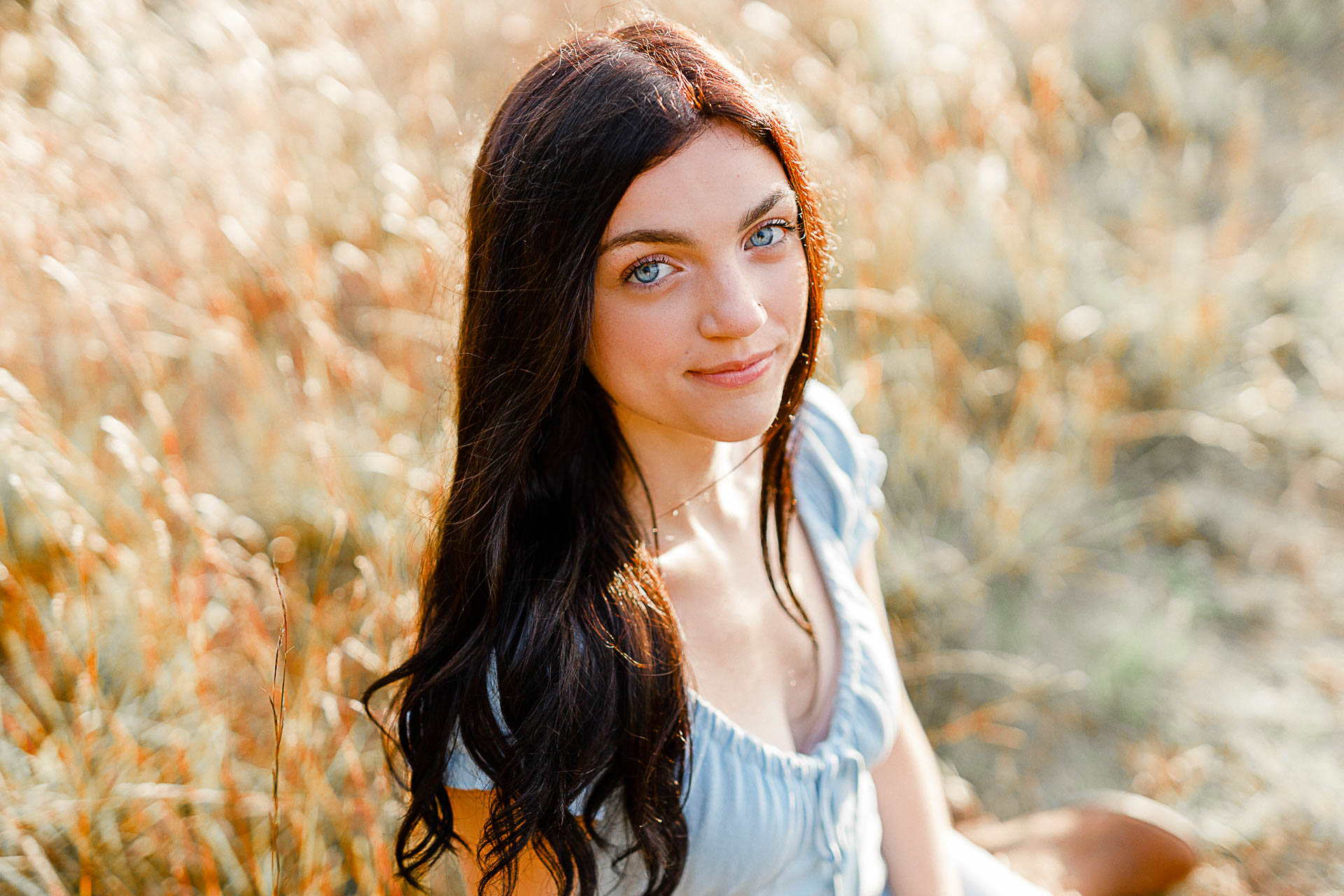 Photo by Duxbury senior photographer Christina Runnals | A high school senior girl with big blue eyes sitting in a golden field