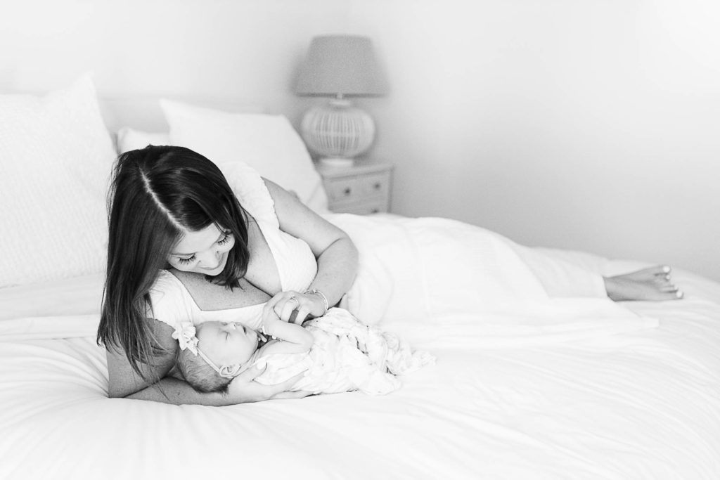 Black and white mom laying with newborn in bed