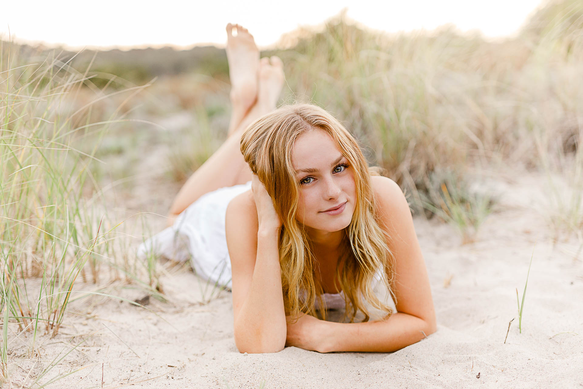 Photo by Plymouth Senior Portrait Photographer Christina Runnals | Girl laying in beach grass wearing a white dress