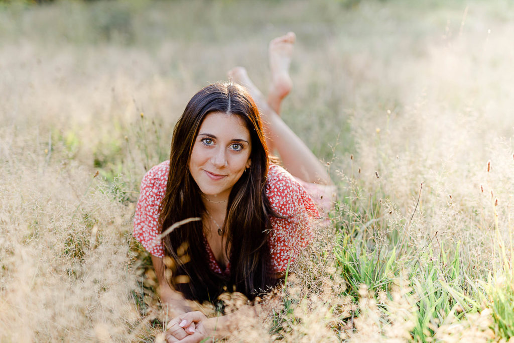 Photo by Norwell Senior Portrait Photographer Christina Runnals | High school girl laying in a golden field 