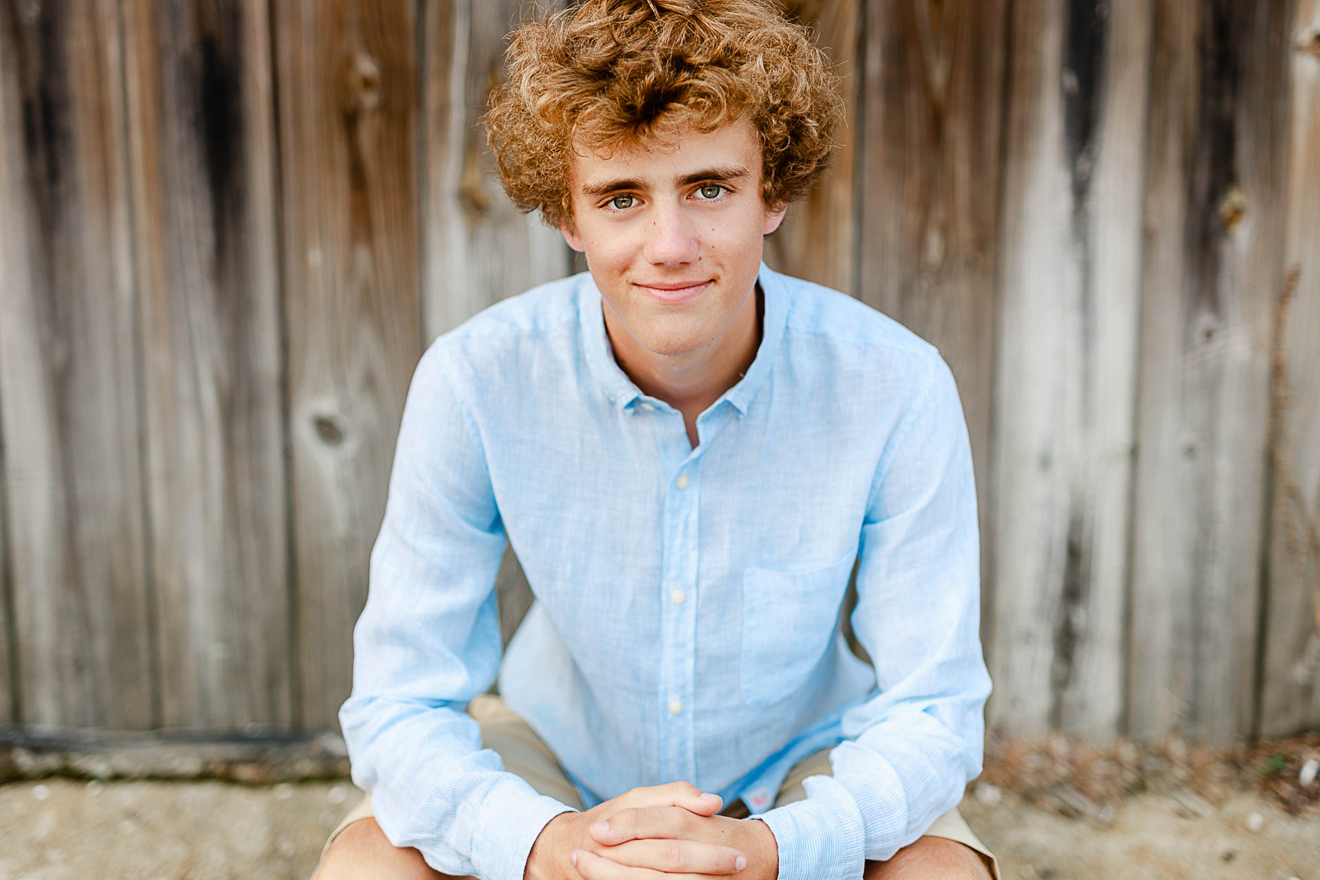 Photo by Scituate Senior Portrait Photographer Christina Runnals | High school senior boy sitting in front of wooden wall