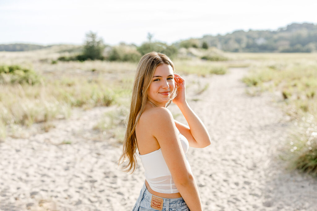 Izzy Monteiro's senior pictures by Scituate MA senior photographer Christina Runnals | senior photos taken on the beach in Massachusetts of girl with long blond hair wearing jeans and a white shirt