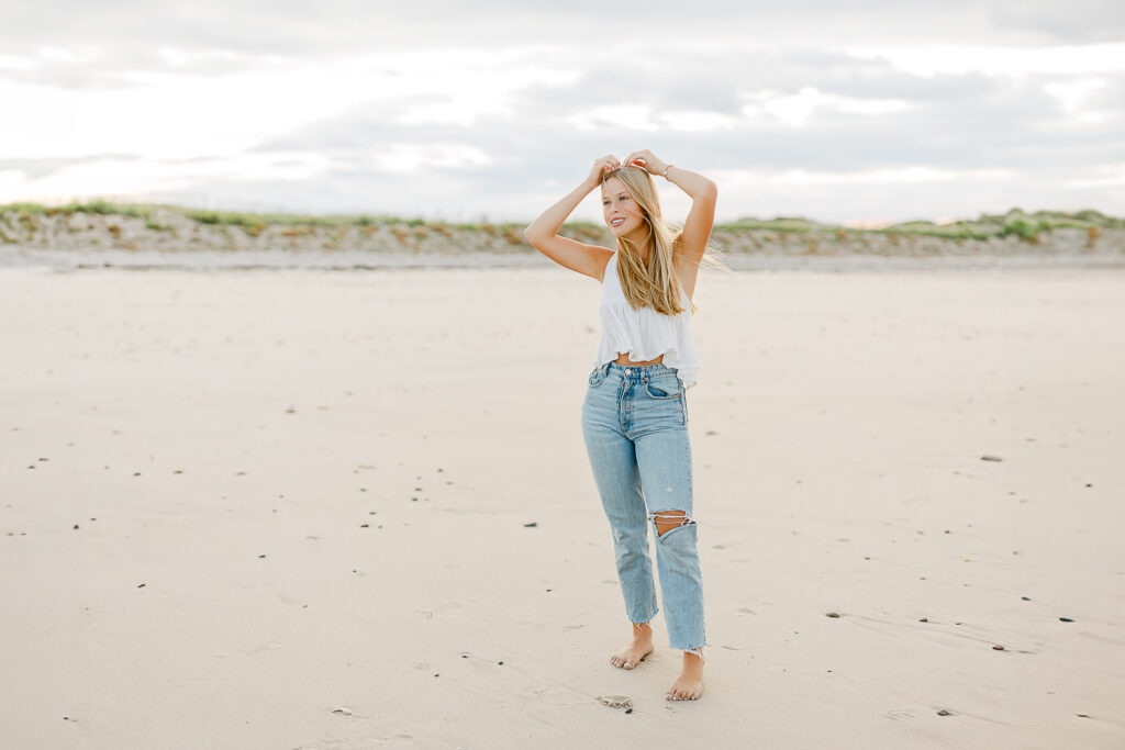 Photo by Massachusetts senior portrait photographer Christina Runnals | High school aged girl standing on the beach smiling into the distance 