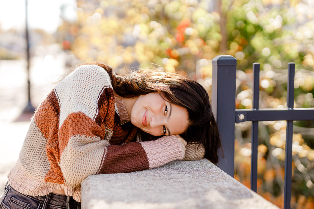 Image by best senior photographer in Massachusetts Christina Runnals | Girl in autumn sweater leaning on gate