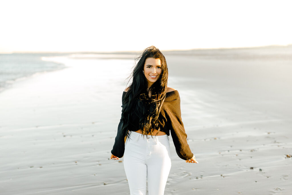 Fall senior pictures in Massachusetts featuring Bella in white denim jeans and a black sweater on the beach.