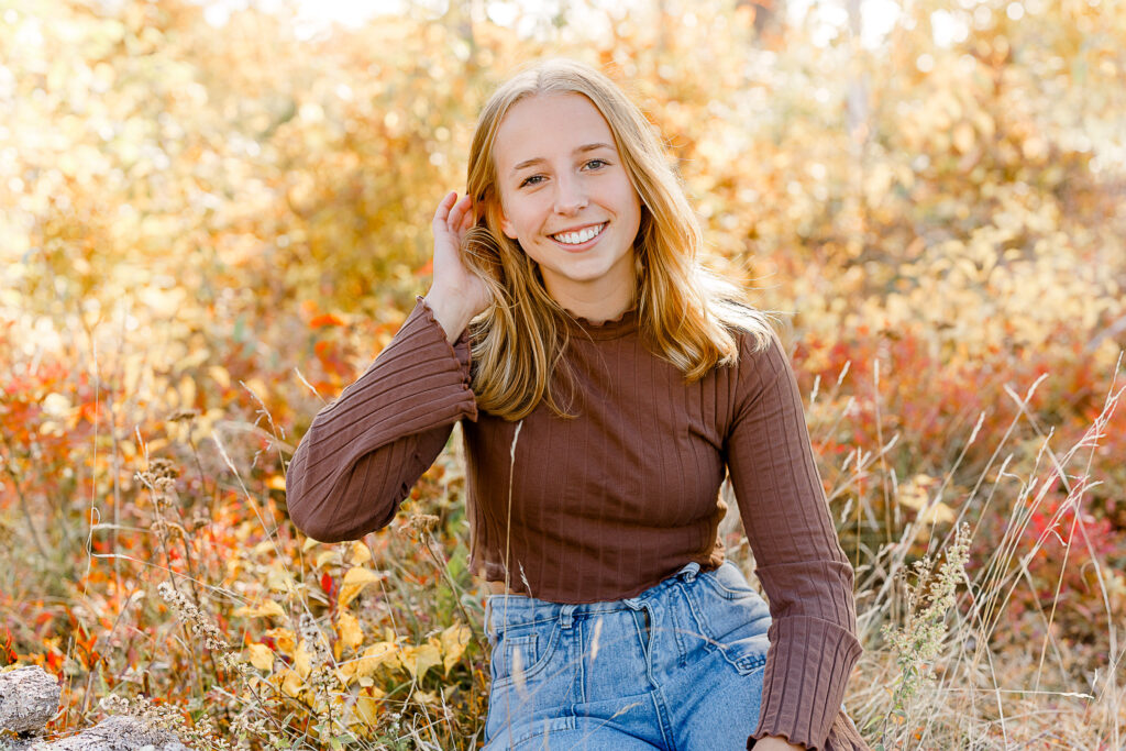 Fall senior pictures in Massachusetts featuring Olyvia in front of a backdrop of golden and red leaves in Maine.