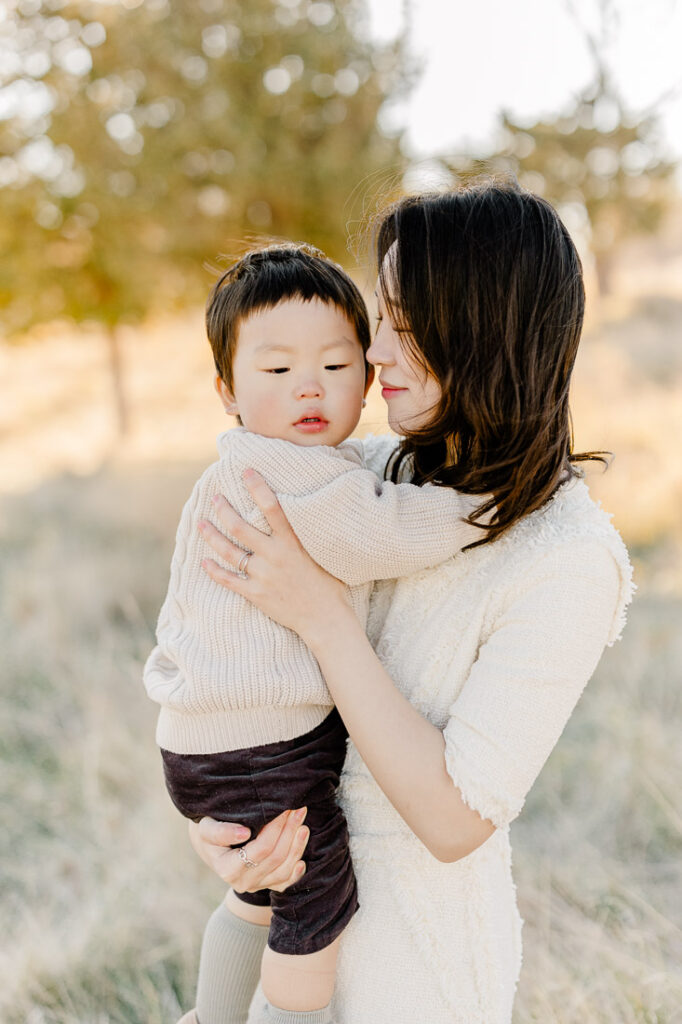 Newton MA family photography featuring a mom, dad, and their little boy in a beautiful field of tall grasses and pine trees