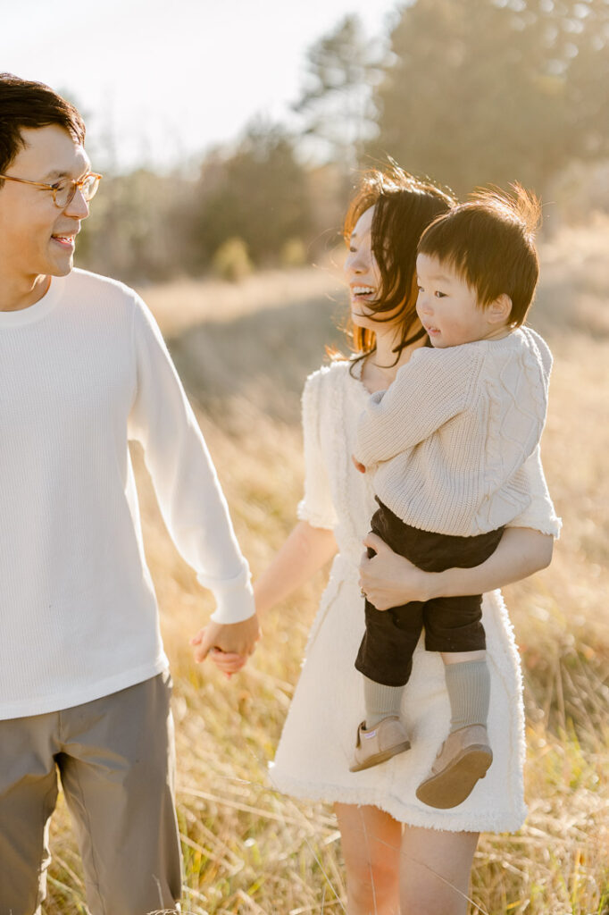 Newton MA family photography featuring a mom, dad, and their little boy in a beautiful field of tall grasses and pine trees