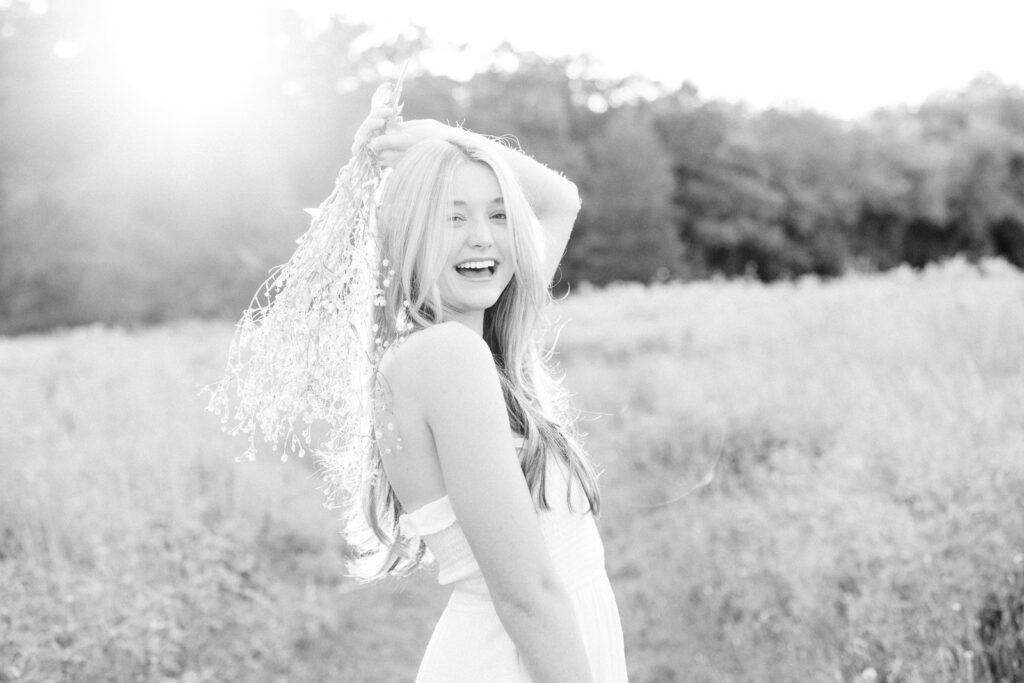 Massachusetts senior photos with wildflowers and a girl wearing a long white dress and laughing