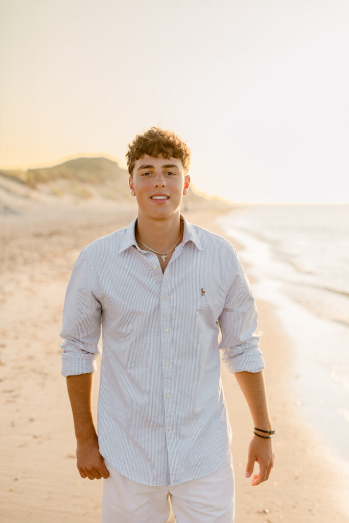 Jack's Nantucket senior pictures taken at sunset walking on the beach in a light blue button down and khaki shorts