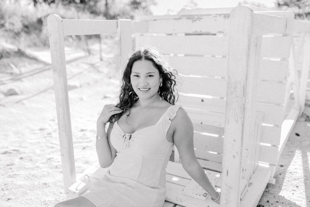 Lexington MA senior pictures taken on the South Shore at a beach.  Featuring a senior with long curly dark brown hair in a short pink dress.  Candid, natural posing.  